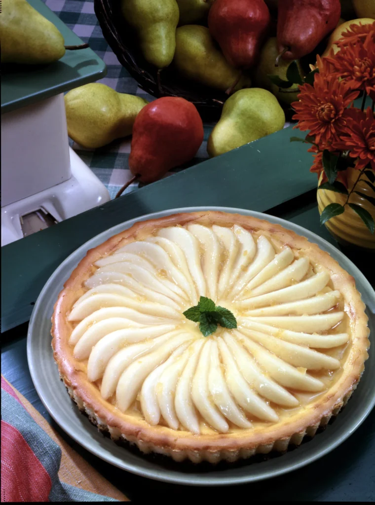 Pear cheesecake topped with sliced pears arranged in a spiral on a tart crust.