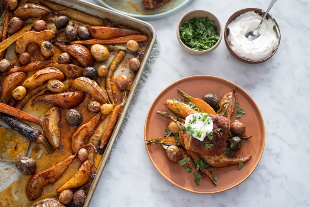 Sheet pan chicken with roasted pears, potatoes, and carrots, served with herbs and a dollop of yogurt.